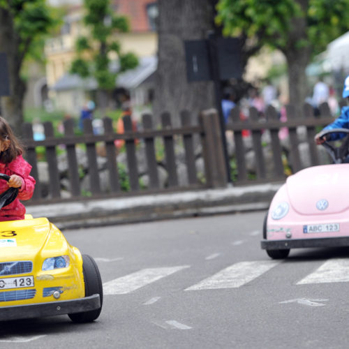 Två barn kör färgglada bilar på en trafiklek