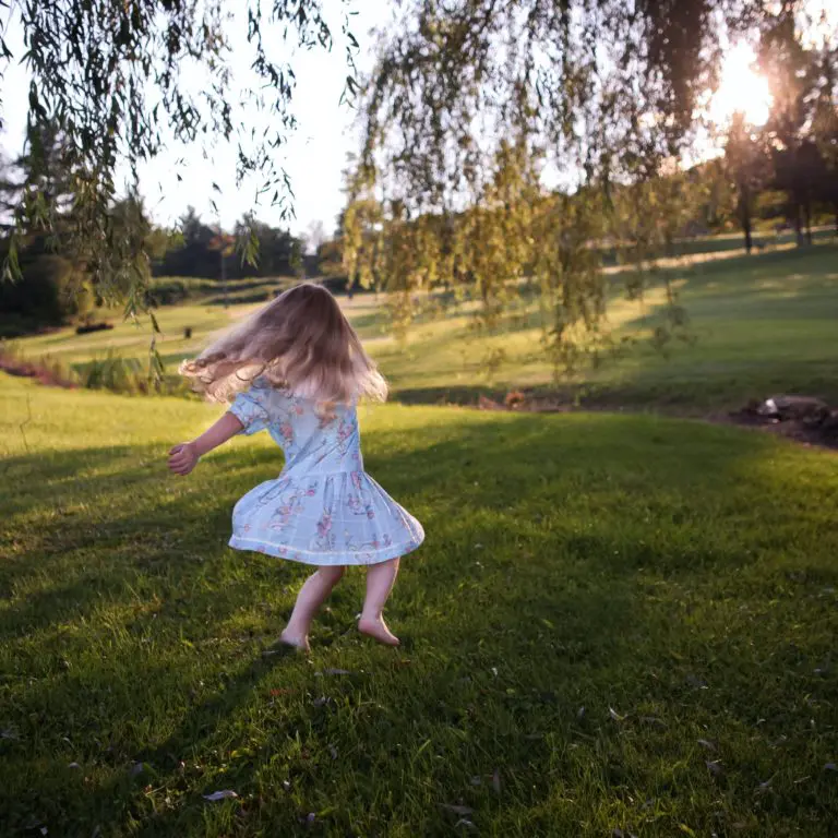 Liten flicka i klänning dansar på en gräsmatta