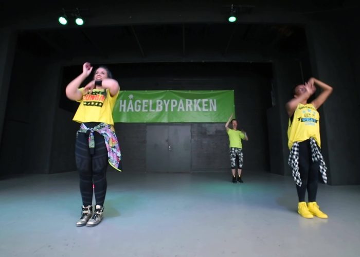 Personer i gula t-shirts dansar zumba på en scen