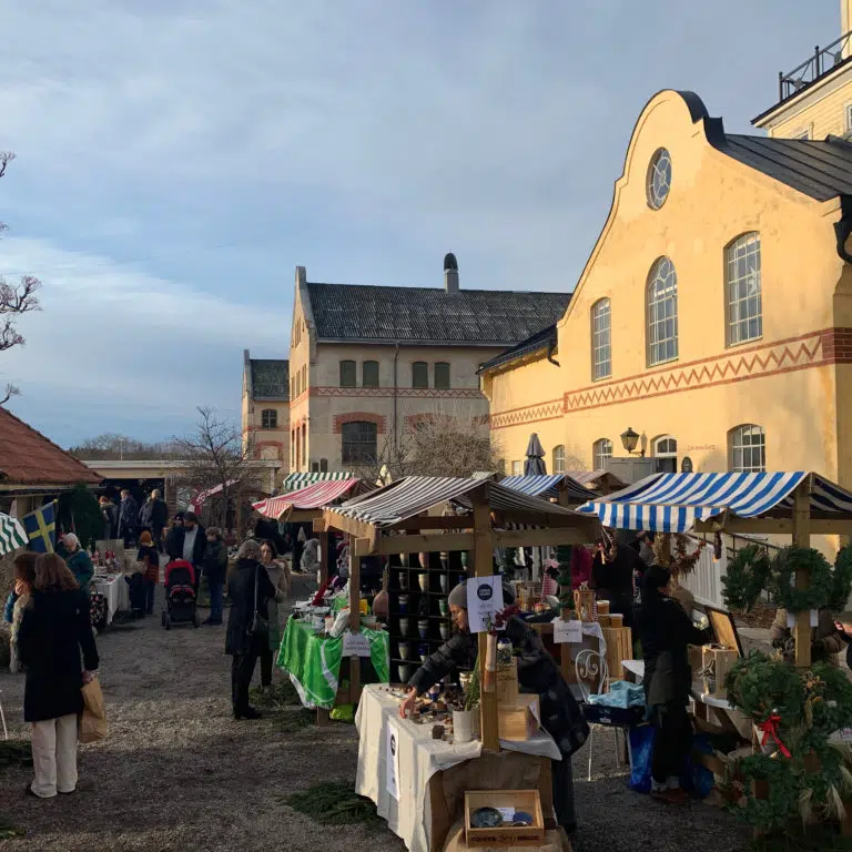 Gula äldre byggnader i betong, julmarknad utomhus med marknadsstånd med randiga tak