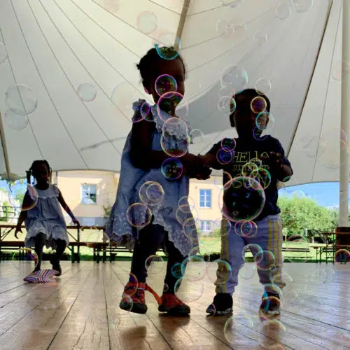 Tre små barn leker med såpbubblor på en dansbana